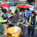 Tony Rivera (right) from the Newmarket Business Improvement District cleans up the street where tents once stood.