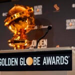 A replcia of a Golden Globe statue appear behind the podium.