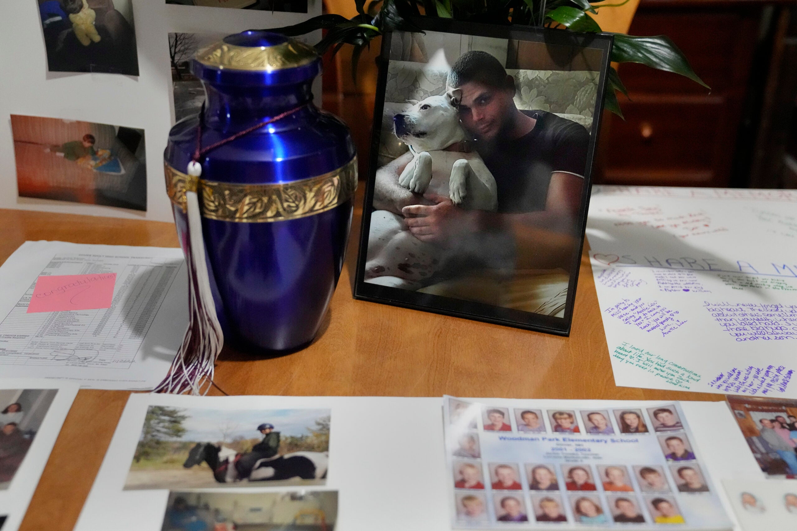 Family photographs of Zach Robinson are displayed on the dining room table next to an urn containing his remains. 