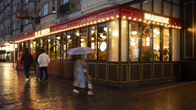 People walk by Blue Ribbon Brasserie in the Fenway-Kenmore neighborhood of Boston.