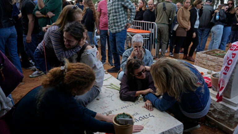 Friends that attended the funeral of 26-year-old Alon Shamriz mourn over the grave of a victim of the Oct. 7th attack buried in the same cemetery in Kibbutz Shefayim, Israel.