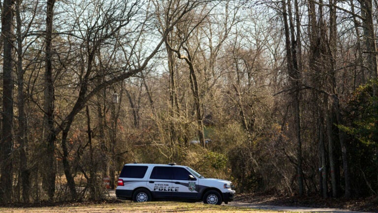 A police vehicle is parked on a road leading to the scene of a helicopter crash in Washington Township, N.J., Wednesday, Dec. 20, 2023.