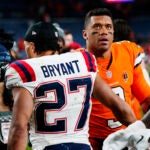 New England Patriots cornerback Myles Bryant, left, greets Denver Broncos quarterback Russell Wilson after an NFL football game at Empower Field at Mile High, Sunday, Dec. 24, 2023, in Denver.