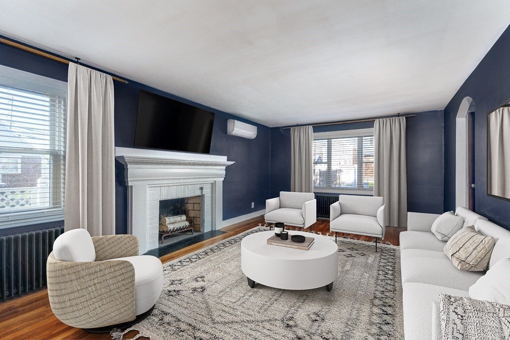 Living room in Quincy home with dark blue walls, wood floors and a white fireplace. 