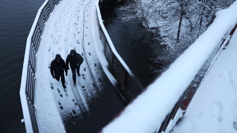 People crossed a snow-covered footbridge as they walked away from Somerville’s Assembly Square.