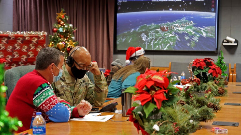 This image provided by the Department of Defense shows volunteers answering phones and emails from children around the globe during the annual NORAD Tracks Santa event on Peterson Air Force Base in Colorado Springs, Colo., Dec. 24, 2021.