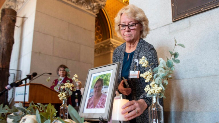 Tracy Wodatch places a candle next to a photo of Joyce Grayson.