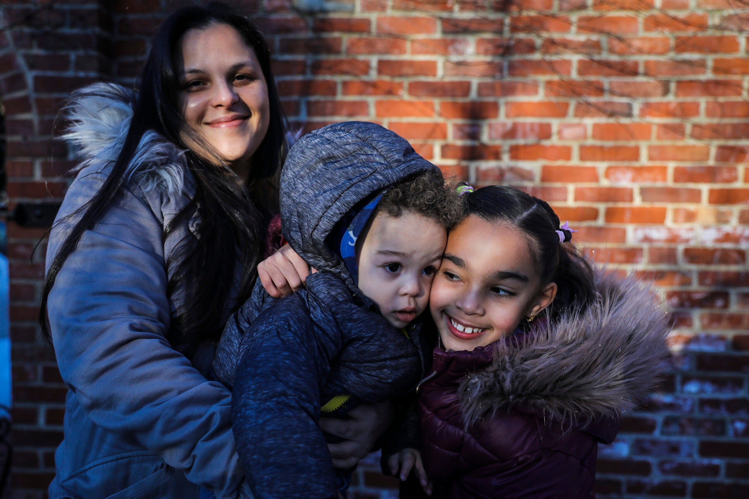Perla Suazo poses for a portrait with her 20-month-old son Liam Suazo and 7-year-old daughter Atziri Suazo in the courtyard of United South End Settlements on Friday. Suazo is part of a guaranteed income program run by United South End Settlements. Since October, over a dozen low-income families were being given no-strings attached money ($800 a month) for 18 months.
