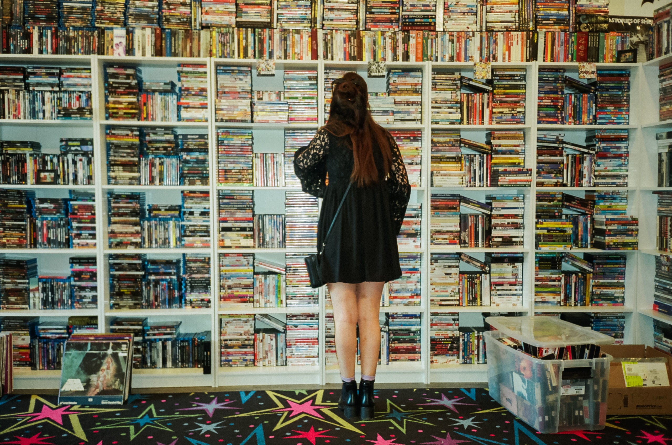 Lauren Kershner browses thousands of analog titles at Be Kind. The store, where customers can buy tapes and rent DVDs, oozes with nostalgia, and movie memorabilia crowds the walls and shelves. 