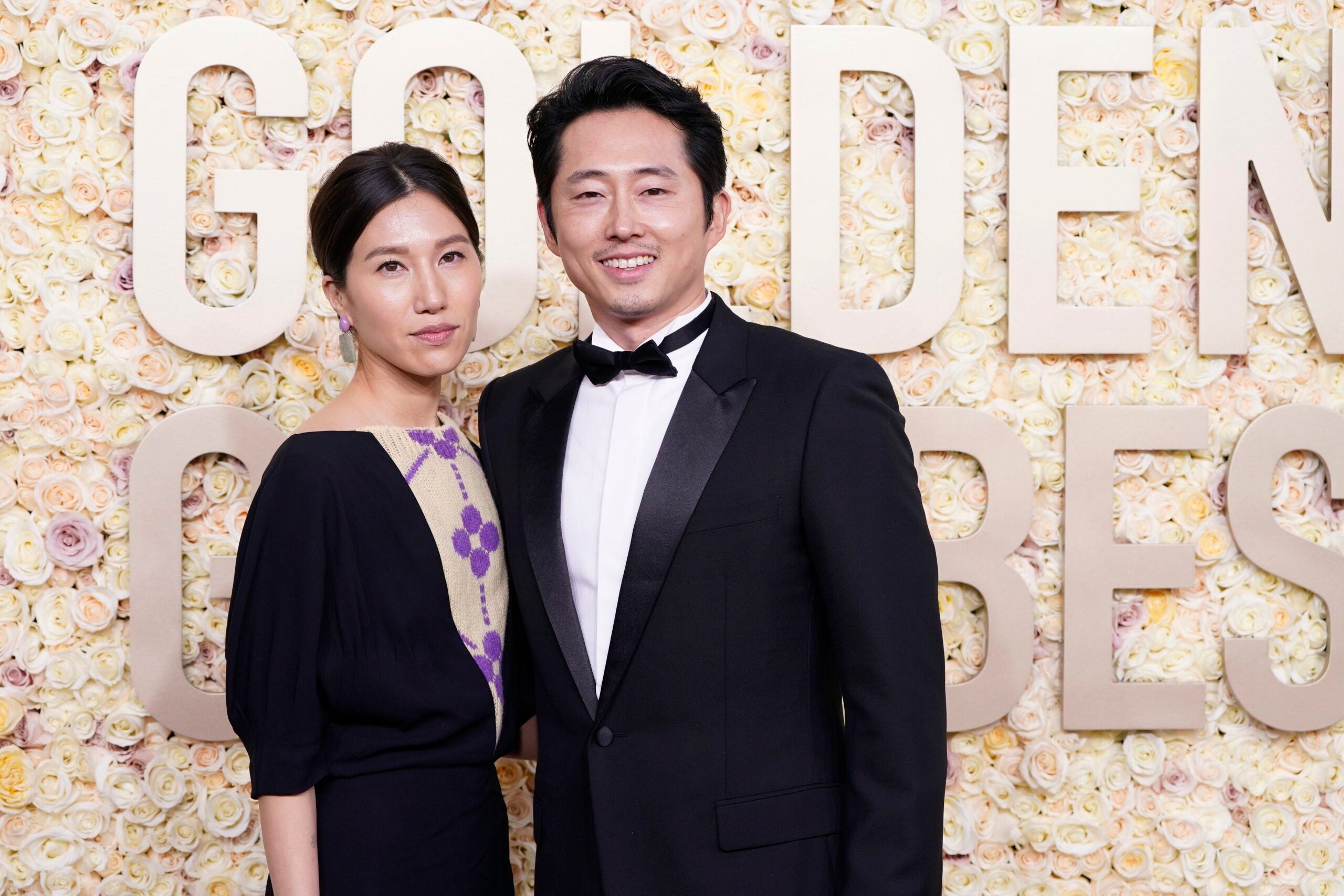 Joana Pak, left, and Steven Yeun arrive at the 2024 Golden Globes red carpet.