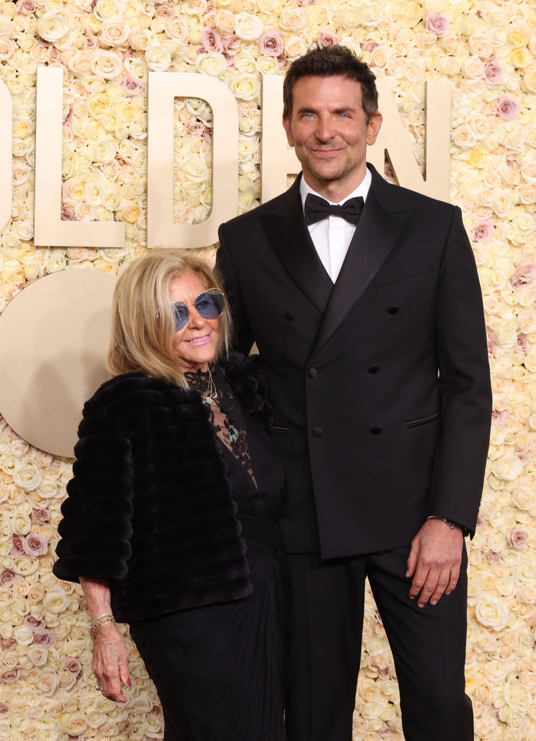 Gloria Campano, left, and Bradley Cooper arrive at the 2024 Golden Globes red carpet.