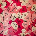A pile of pink, red, and white paper hearts featuring the names of ex-lovers, ex-friends, and more.
