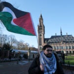 A protester waving the Palestinian flag stands outside the Peace Palace.