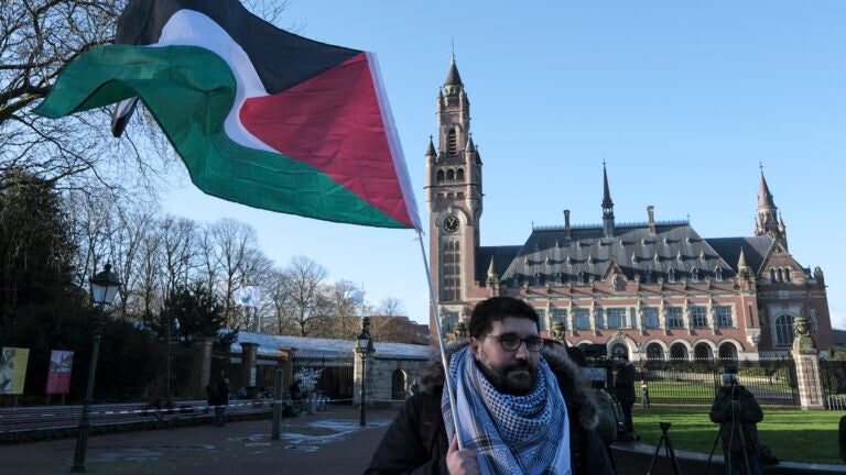 A protester waving the Palestinian flag stands outside the Peace Palace.