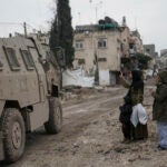 A Palestinian woman flashes a V-sign towards Israeli troops.