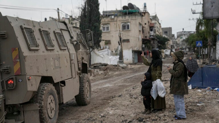 A Palestinian woman flashes a V-sign towards Israeli troops.
