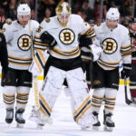 An injured Boston Bruins goaltender Linus Ullmark (35) is helped off the ice by defenseman Kevin Shattenkirk (12), left wing Jake DeBrusk (74) and a member of the training staff during overtime of the team's NHL hockey game against the Arizona Coyotes on Tuesday, Jan. 9, 2024, in Tempe, Ariz. The Coyotes won 4-3.