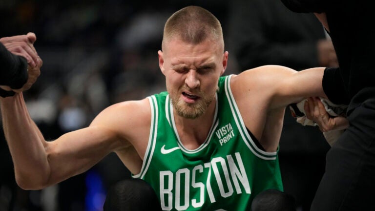 Boston Celtics center Kristaps Porzingis (8) gets helped up after injuring his eye while playing the Indiana Pacers during the first half of an NBA basketball game in Indianapolis, Saturday, Jan. 6, 2024.