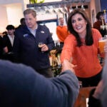 Republican presidential candidate former UN Ambassador Nikki Haley shakes hands with a patron during a campaign stop at a restaurant, Monday, Jan. 22, 2024, in Concord, N.H. At left is N.H. Gov. Chris Sununu.