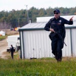 A police officer gives an order to the public during a manhunt for Robert Card.