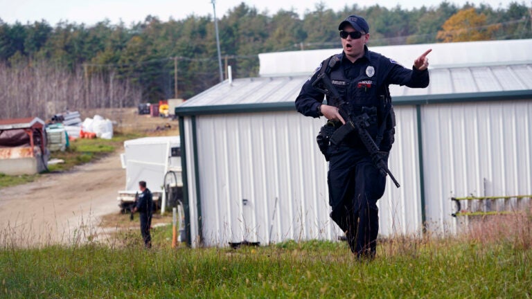 A police officer gives an order to the public during a manhunt for Robert Card.