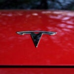 A Tesla logo is seen on a red vehicle.