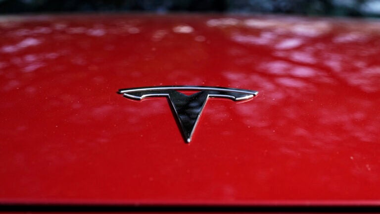 A Tesla logo is seen on a red vehicle.