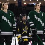 LOWELL, MASSACHUSETTS - JANUARY 03: Hilary Knight #21 of Boston and Megan Keller #5 look on during the national anthem before the PWHL game against Minnesota at Tsongas Center on January 03, 2024 in Lowell, Massachusetts.