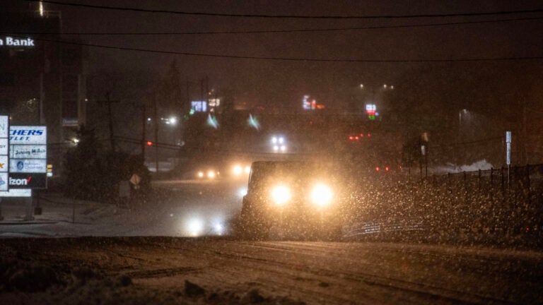 Cars driving at night while it snows in Massachusetts.