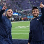 Minneapolis, MN 2/4/2018: Steve Belichick (left) and his brother Brian Belichick (right), the sons of Patriots head coach Bill Belichick, smile and point to some friends in the stands who were calling out to them around two hours before kickoff. The New England Patriots play the Philadelphia Eagles in Super Bowl LII at US Bank Stadium in Minneapolis.