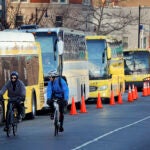 Cyclists negotiate Kenmore Square where shuttle buses line up to replace train service on Jan. 3, 2024.