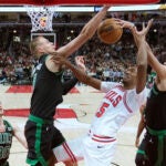 Boston Celtics' Derrick White, right, blocks the shot of Chicago Bulls' Julian Phillips, second from right, as Celtics' Kristaps Porzingis, second from left, also defends during the first half.