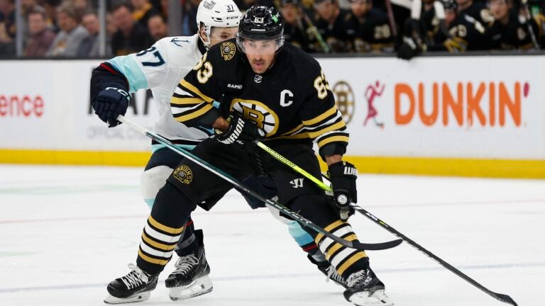 Brad Marchand #63 of the Boston Bruins shields Yanni Gourde #37 of the Seattle Kraken from the puck during the first period at TD Garden on February 15, 2024 in Boston, Massachusetts.