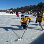 Hockey players go for the puck during the final of the women's open division at the Pond Hockey Classic in Meredith, N.H.