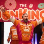 Ben Affleck, with his hands up and performing a song, in a Dunkin' ad.