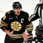 With blood trickling down his nose, Boston Bruins left wing Brad Marchand (63) argues with officials after drawing a penalty during an altercation with Calgary Flames center Martin Pospisil during the first period of an NHL hockey game, Tuesday, Feb. 6, 2024, in Boston.