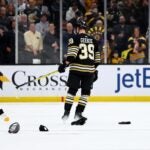 Morgan Geekie of the Bruins skates past hats thrown on the ice after he scored a hat trick against the Vegas Golden Knights at TD Garden.