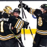 Bruins goaltender Jeremy Swayman is embraced by Brad Marchand as Charlie McAvoy, right, skates in for a hug following a shootout win.