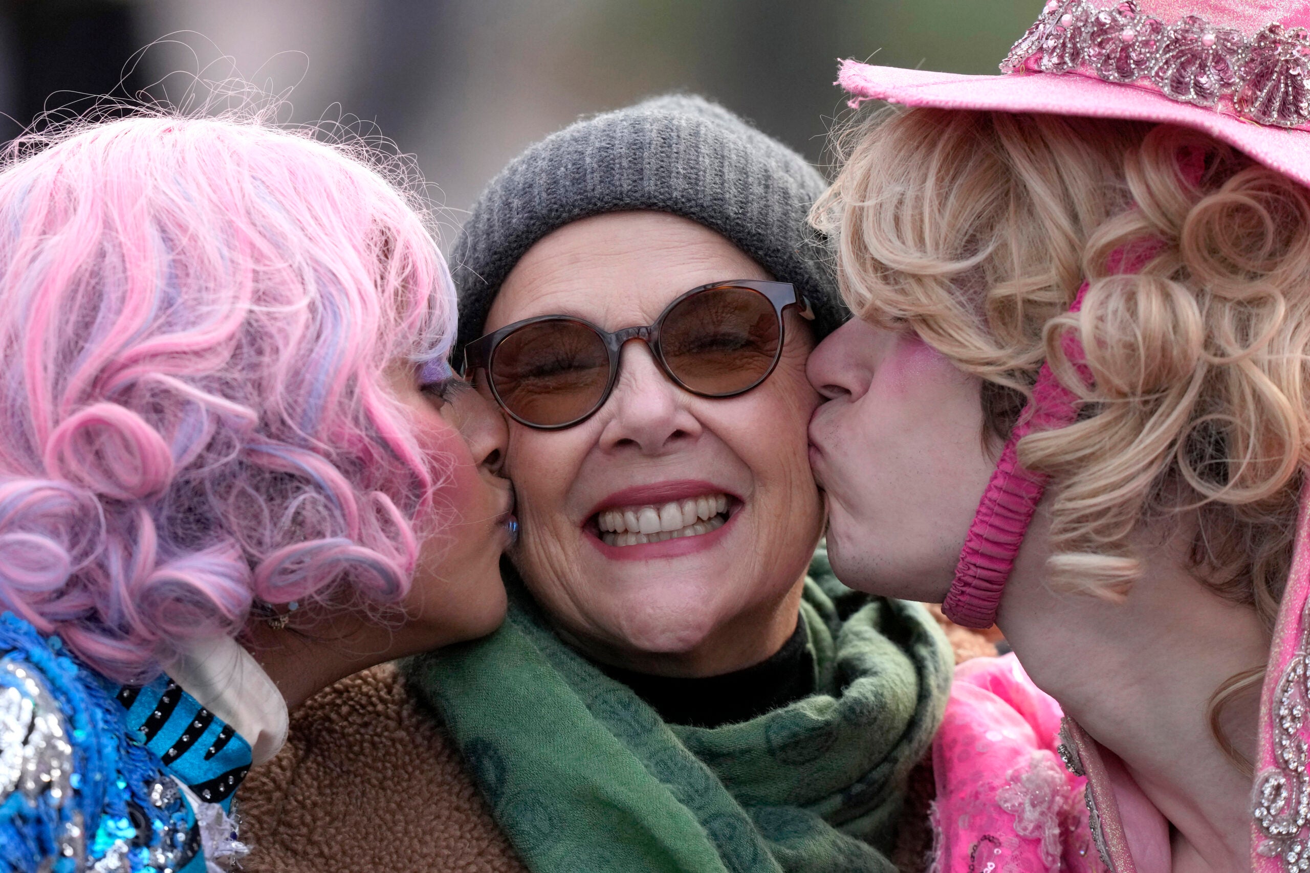 Actor Annette Bening, center, Hasty Pudding 2024 Woman of the Year, receives a kiss from Harvard University theatrical students Nikita Nair, left, and Joshua Hillers, right.