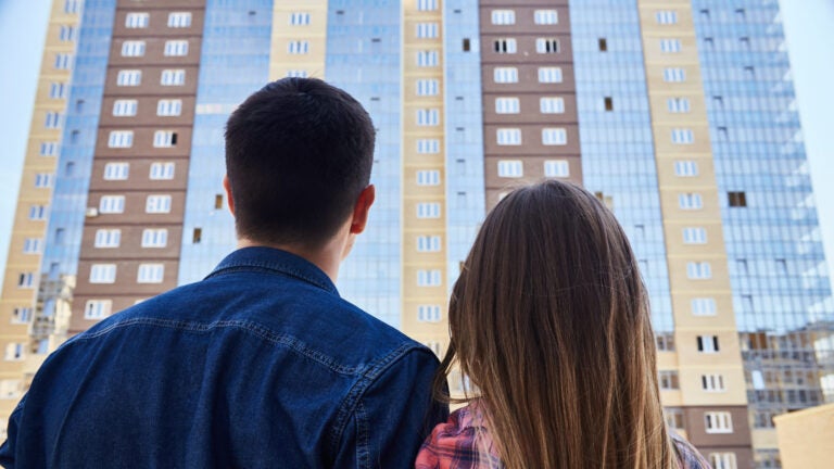 A young couple looks at an apartment building