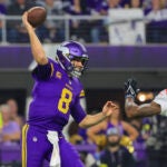 Minnesota Vikings Kirk Cousins completes a pass with pressure from New England Patriots Jalen Mills during third quarter NFL action at U.S. Bank Stadium.