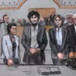 In this courtroom sketch, Boston Marathon bomber Dzhokhar Tsarnaev, center, stands with his defense attorneys as a death by lethal injection sentence is read in the penalty phase of his trial in Boston, Friday, May 15, 2015.