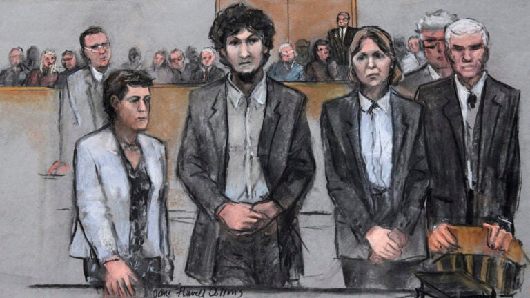 In this courtroom sketch, Boston Marathon bomber Dzhokhar Tsarnaev, center, stands with his defense attorneys as a death by lethal injection sentence is read in the penalty phase of his trial in Boston, Friday, May 15, 2015.