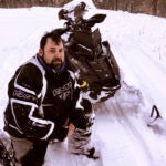 Jeffrey Smith poses with a snowmobile.