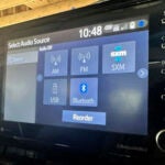 A display screen inside a vehicle shows various radio options.