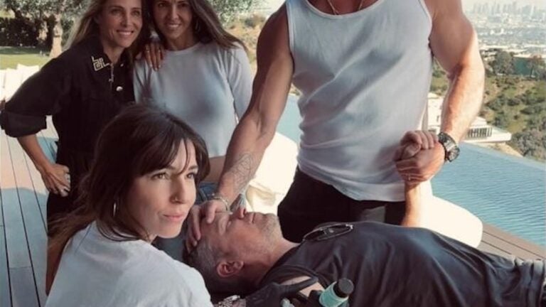 Matt Damon gets a new tattoo from Corina Weikl while Chris Hemsworth holds his hand and Luciana Damon and Hemsworth's wife, Elsa Pataky, look on.