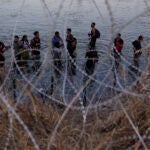 FILE - Migrants wait to climb over concertina wire after they crossed the Rio Grande and entered the U.S. from Mexico, Sept. 23, 2023, in Eagle Pass, Texas.