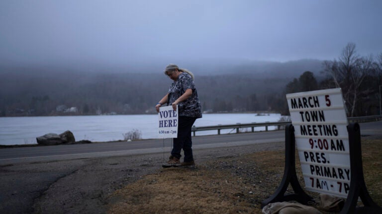 Town Clerk Sandra Lacasse, places a sign outside the town office n Elmore, Vt.