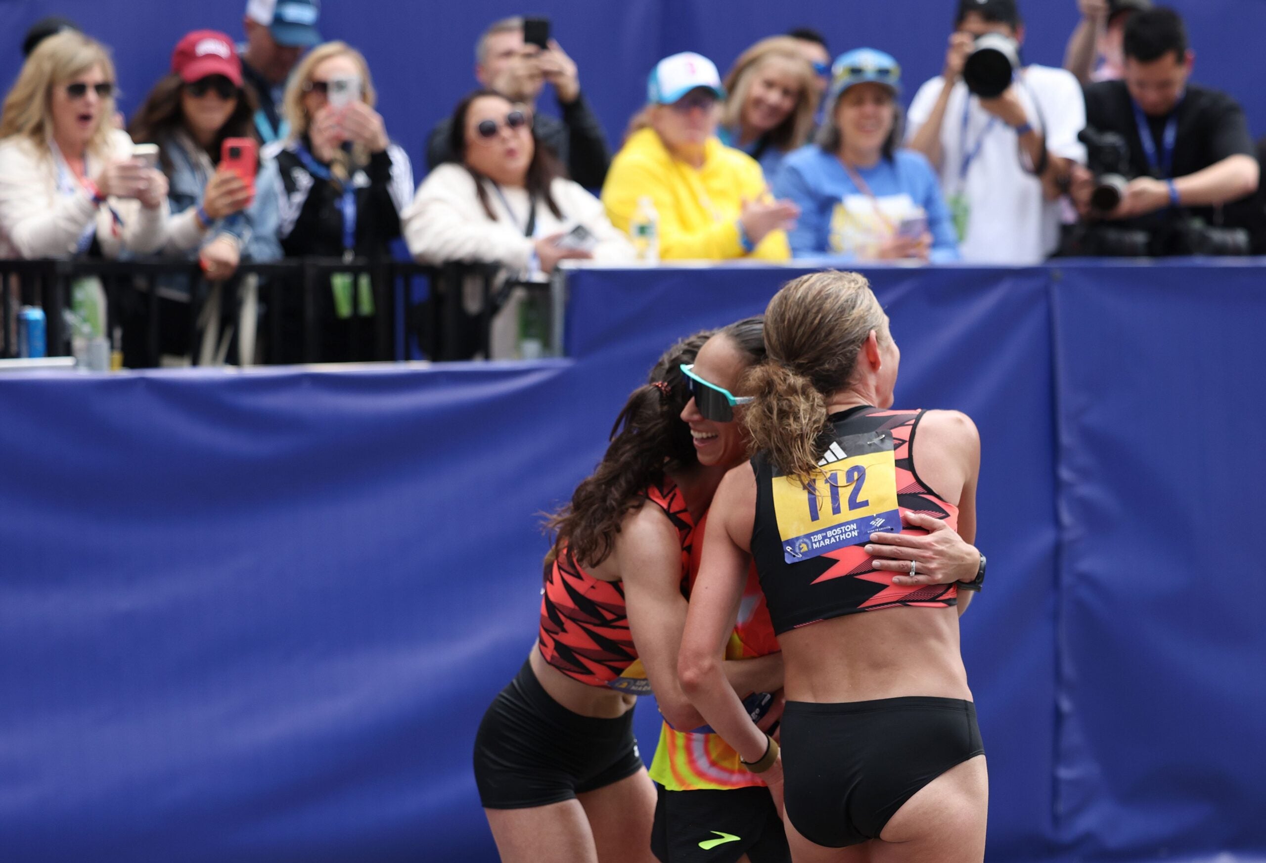 Americans Emma Bates, Des Linden, and Sara Hall embrace after crossing the Finish Line of the Boston Marathon on Monday, April 15, 2024.