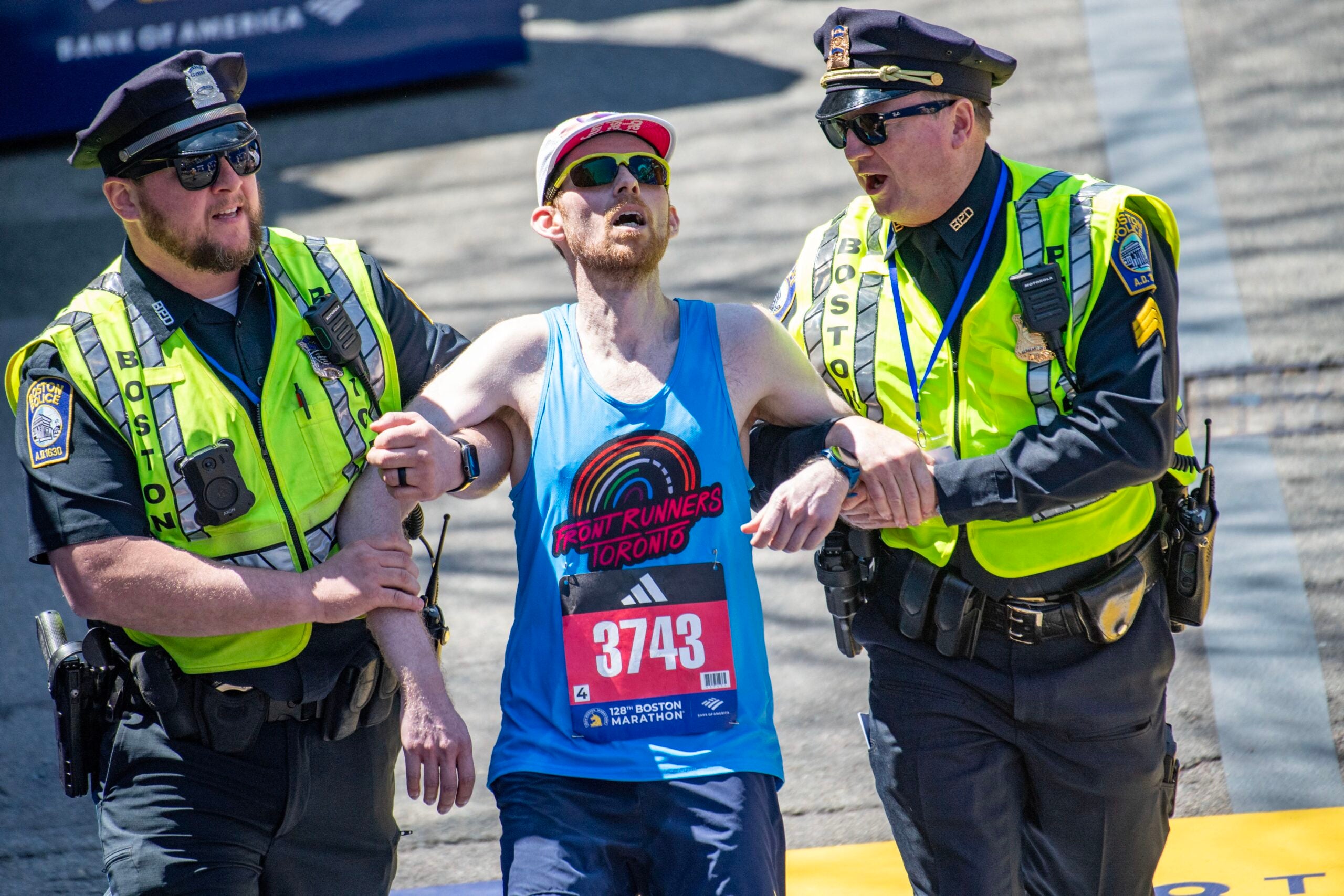 Un corridore viene aiutato a tagliare il traguardo dagli agenti di polizia durante la 128a maratona di Boston il 15 aprile 2024 a Boston, Massachusetts.